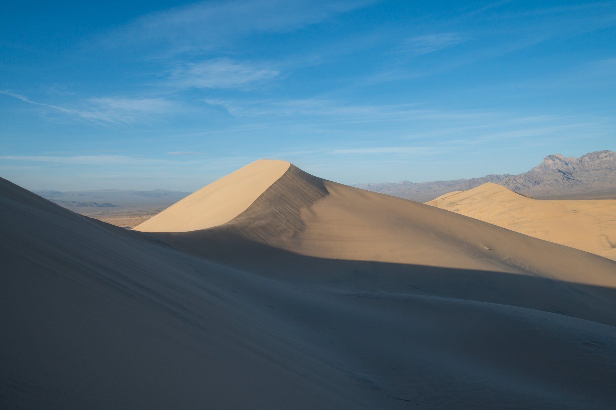 A sand dune ridge in the Kelso Dunes at sunset, half in shadow.
